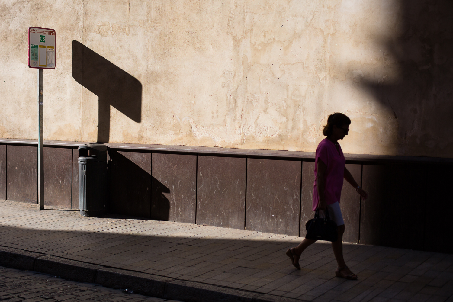 Une femme marche à l'ombre dans une rue de Seville.